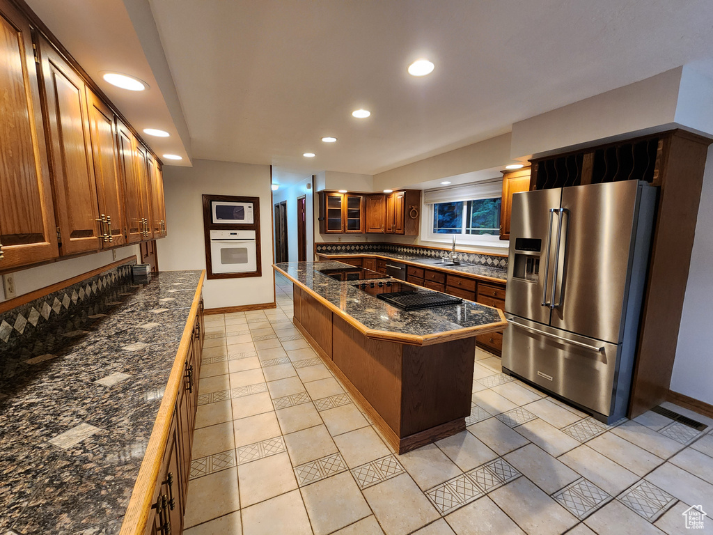 Kitchen with white appliances, recessed lighting, tile counters, baseboards, and glass insert cabinets