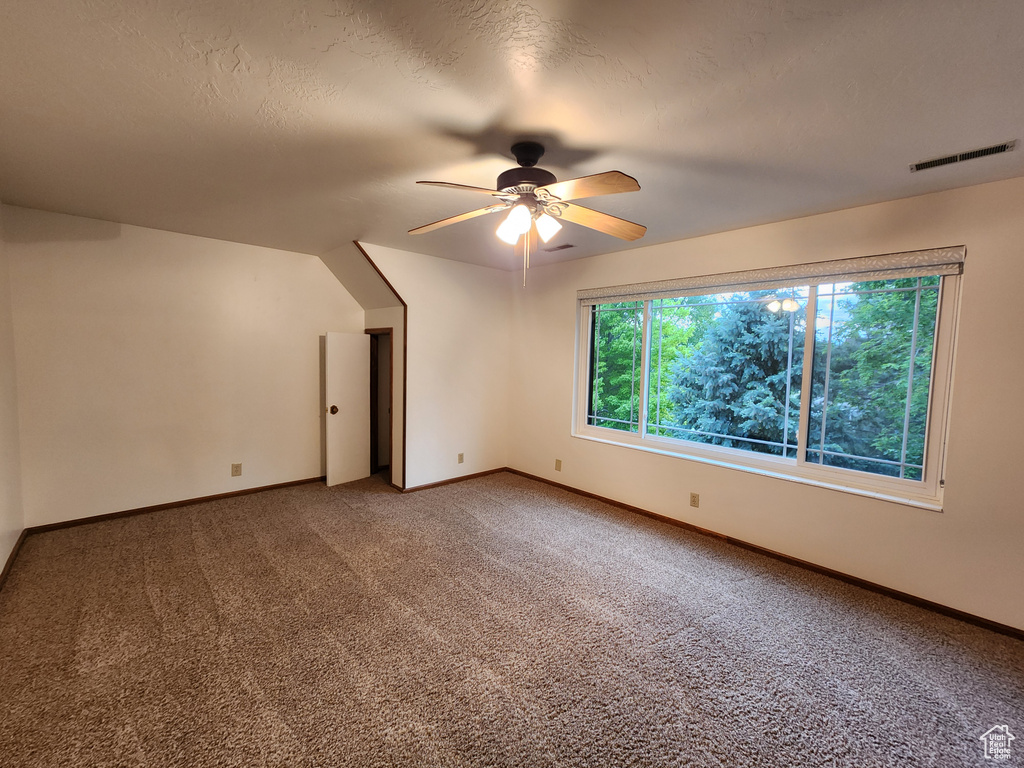 Carpeted spare room with a ceiling fan and baseboards