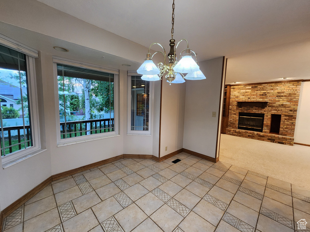 Unfurnished dining area with plenty of natural light, a fireplace, baseboards, and a chandelier