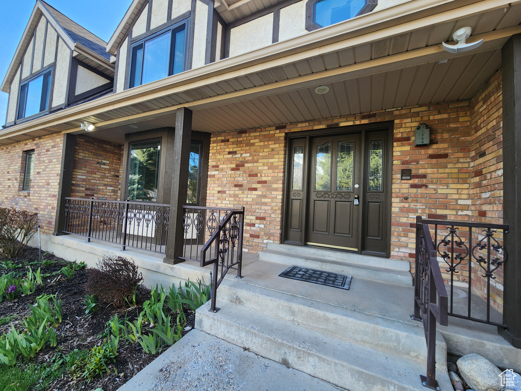 Doorway to property featuring a porch and brick siding