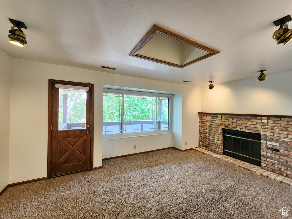 Unfurnished living room with carpet floors, a fireplace, and baseboards