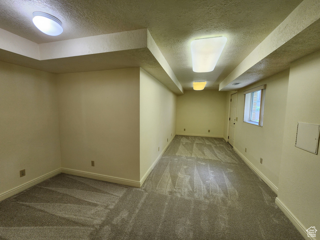 Below grade area with a textured ceiling, carpet floors, and baseboards