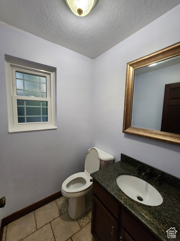 Bathroom with toilet, baseboards, vanity, and a textured ceiling