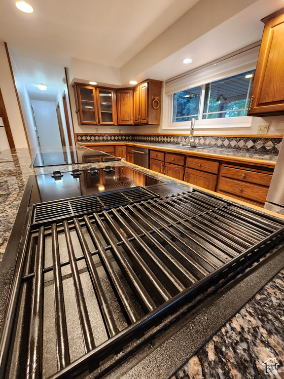Kitchen with a sink, brown cabinetry, recessed lighting, decorative backsplash, and dark countertops