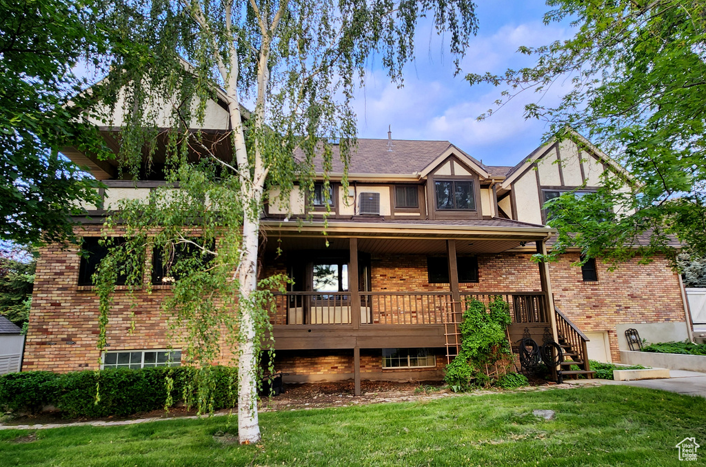 Tudor-style house with a front lawn, brick siding, stairs, and stucco siding
