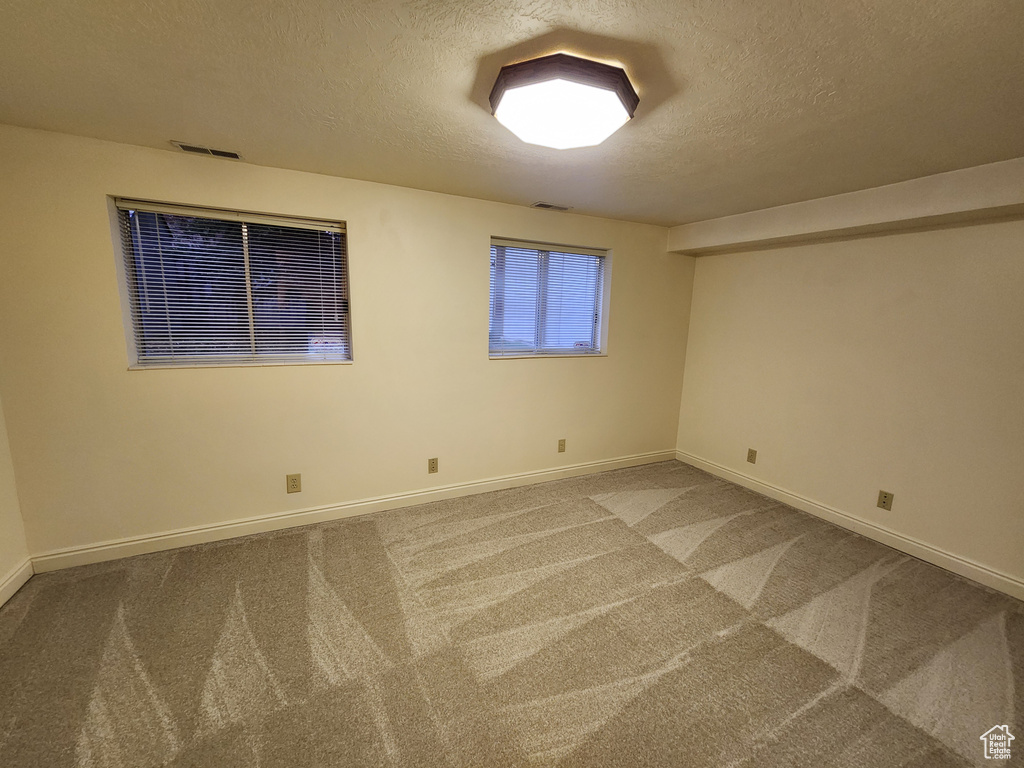Unfurnished room with a textured ceiling, carpet, and baseboards