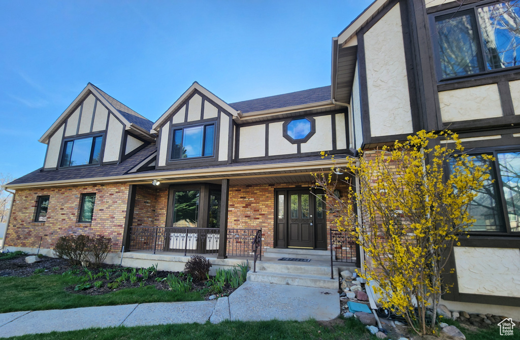 Tudor house with covered porch, stucco siding, and brick siding