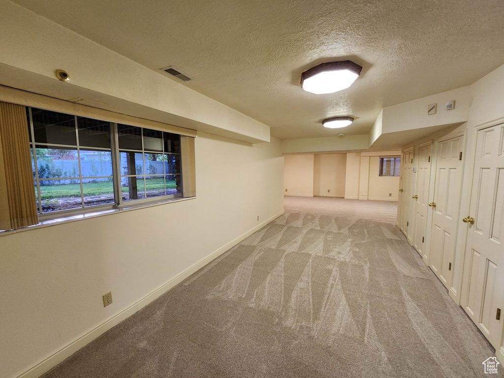 Spare room featuring a textured ceiling, baseboards, and light colored carpet