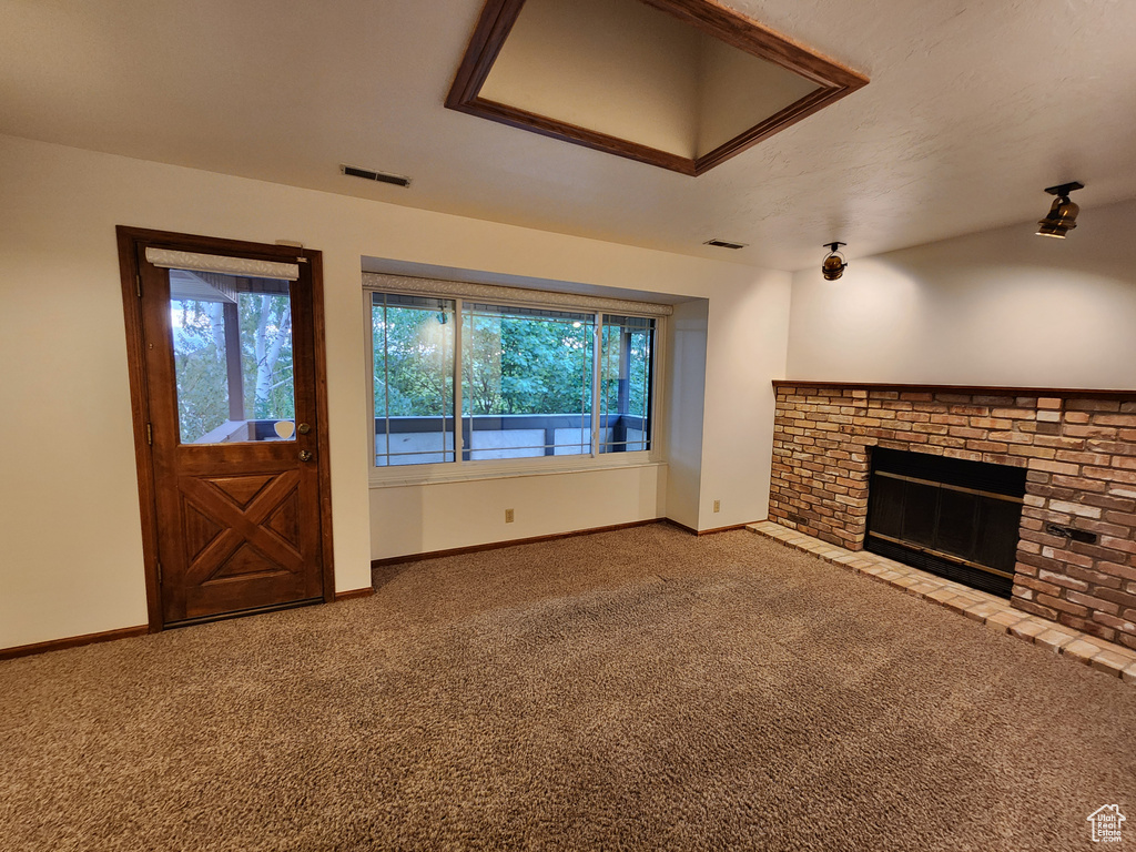 Unfurnished living room featuring carpet flooring, healthy amount of natural light, and a fireplace