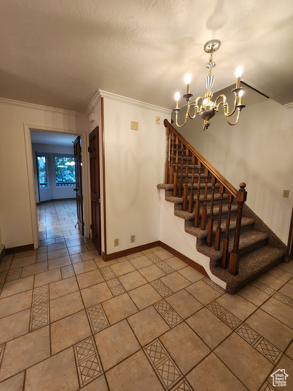 Stairs featuring ornamental molding, baseboards, and a chandelier