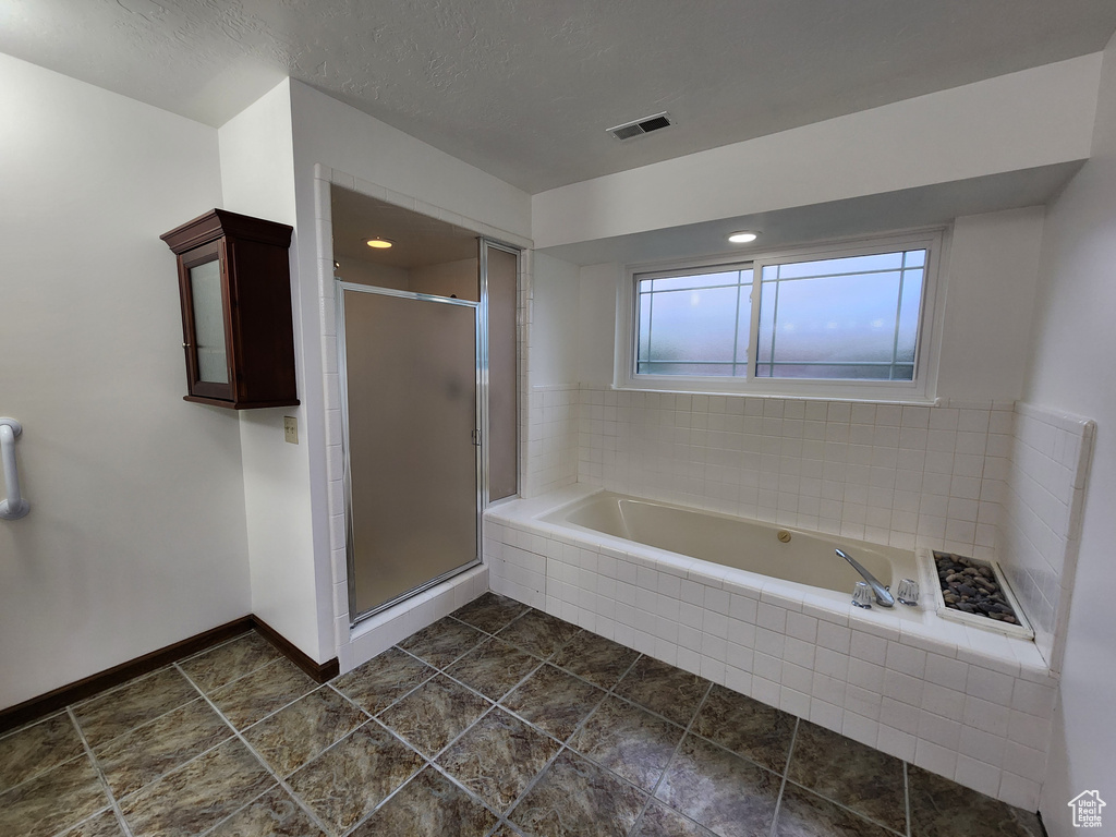 Full bathroom with a shower stall, a bath, baseboards, and tile patterned floors
