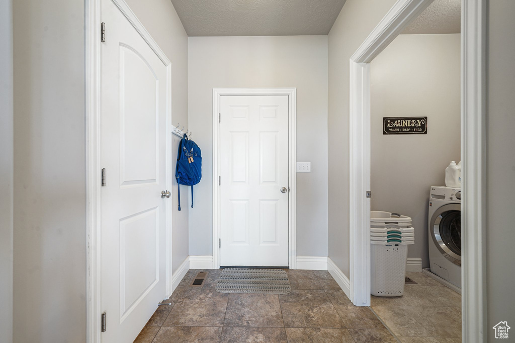 Washroom featuring washer / dryer, baseboards, stone finish floors, and a textured ceiling