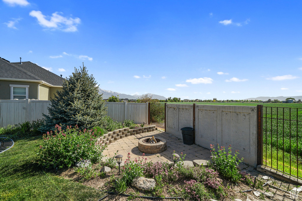 Fenced backyard featuring an outdoor fire pit, a mountain view, and a patio