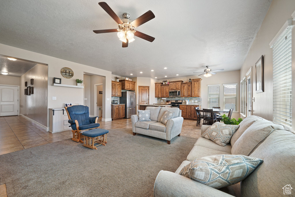 Living room with ceiling fan, light tile patterned flooring, a textured ceiling, light carpet, and recessed lighting