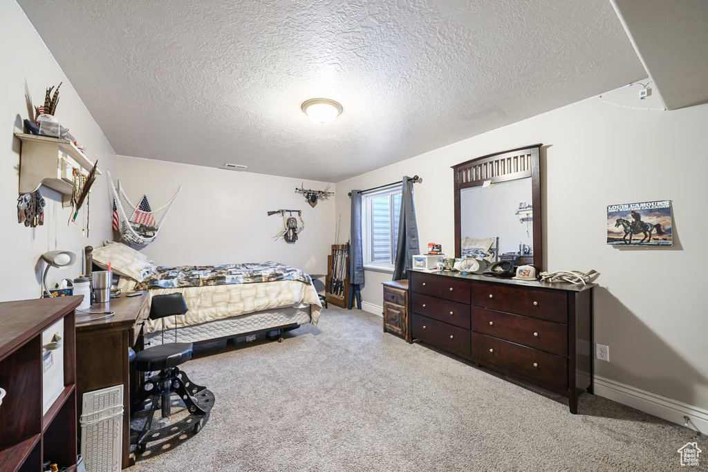 Carpeted bedroom with a textured ceiling and baseboards