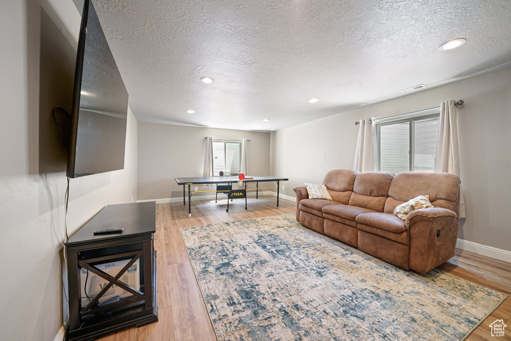 Living area with a textured ceiling, wood finished floors, baseboards, and recessed lighting