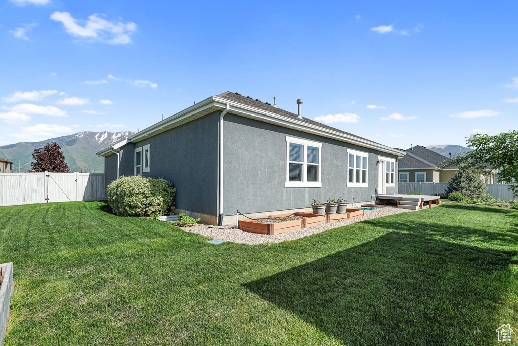 Rear view of property featuring a mountain view, a gate, stucco siding, and a vegetable garden