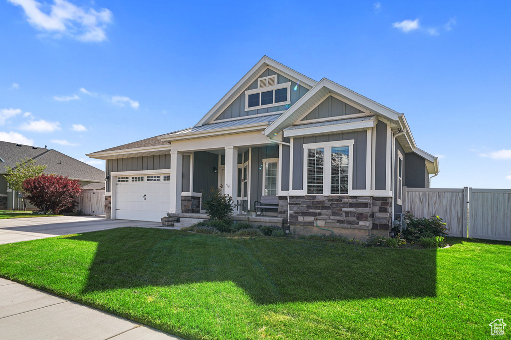 Craftsman house featuring board and batten siding, a porch, driveway, stone siding, and an attached garage