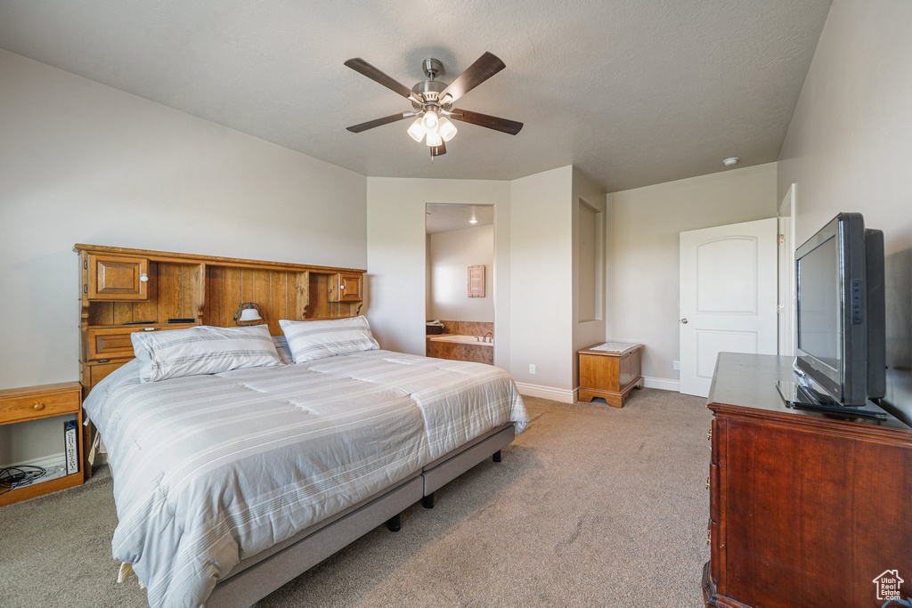 Bedroom featuring light colored carpet, baseboards, a ceiling fan, and ensuite bath