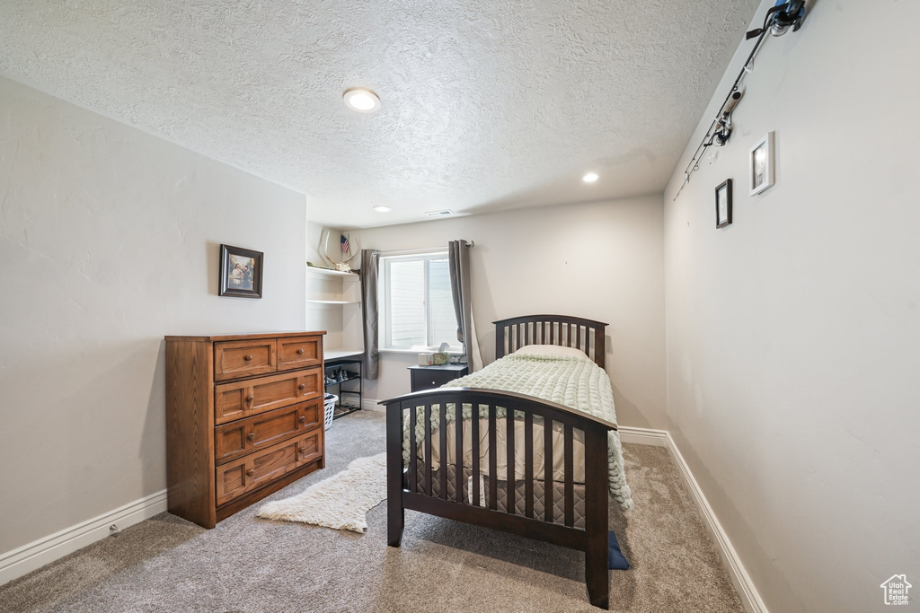 Carpeted bedroom featuring a textured ceiling, recessed lighting, and baseboards