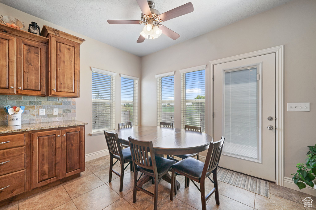 Dining area featuring light tile patterned floors, baseboards, and a ceiling fan