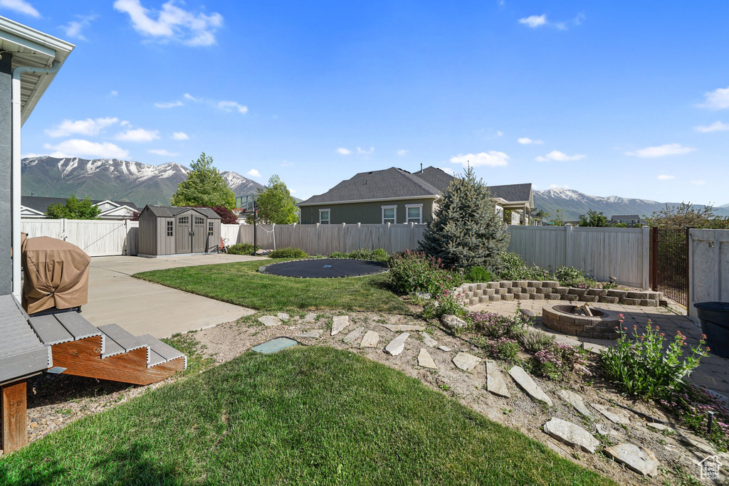 View of yard featuring an outdoor fire pit, a storage shed, a patio, and a mountain view