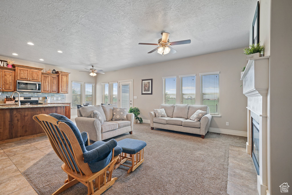 Living area featuring ceiling fan, a textured ceiling, recessed lighting, baseboards, and a fireplace