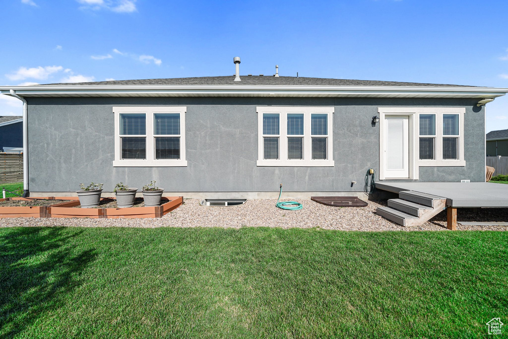 Rear view of house with a garden, a lawn, and stucco siding