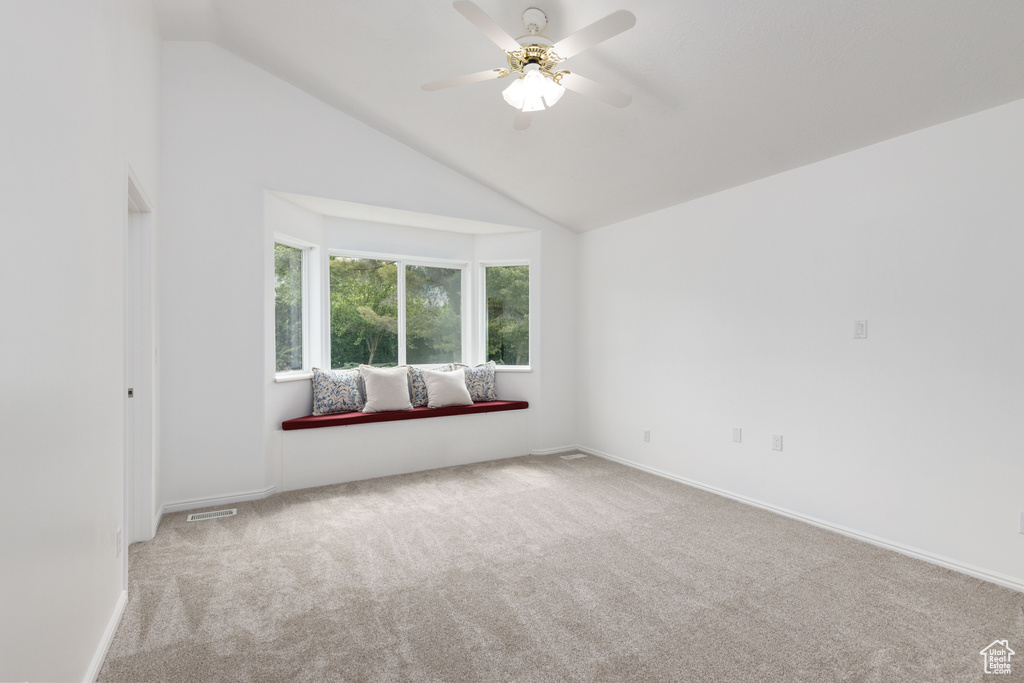 Carpeted empty room with a ceiling fan, lofted ceiling, and baseboards