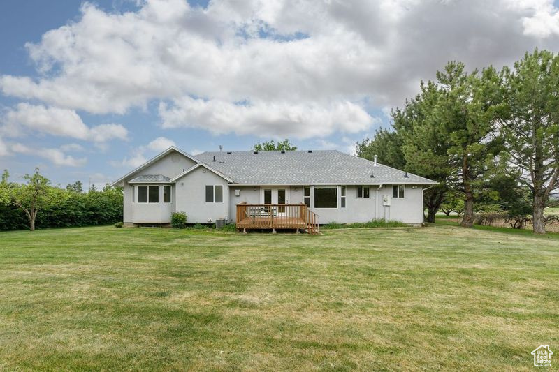 Back of property with a wooden deck and a yard