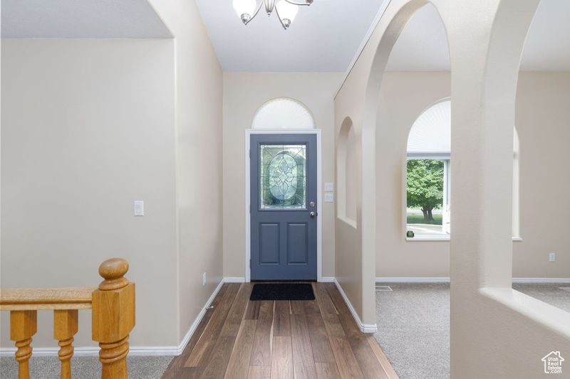 Foyer entrance with wood-type flooring, baseboards, and arched walkways