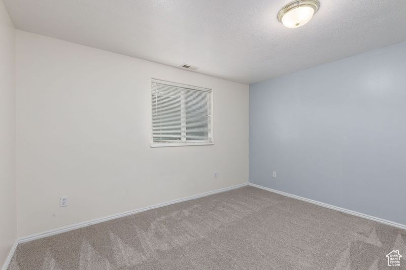 Carpeted empty room featuring baseboards and a textured ceiling