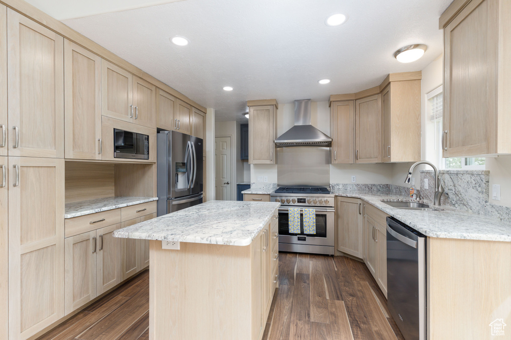 Kitchen with appliances with stainless steel finishes, wall chimney range hood, a sink, light brown cabinetry, and recessed lighting
