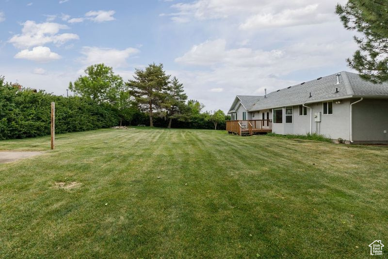View of grassy yard with a deck