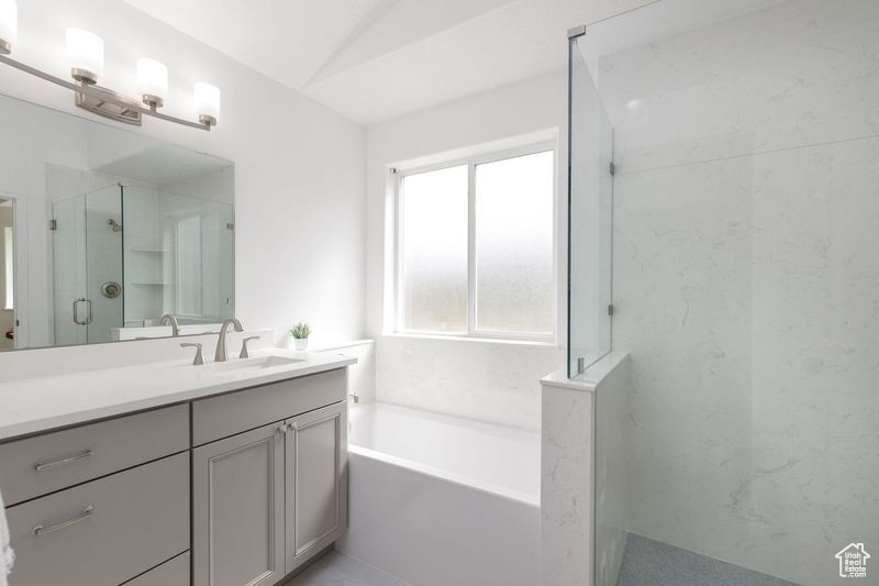 Bathroom featuring a stall shower, vanity, and a garden tub