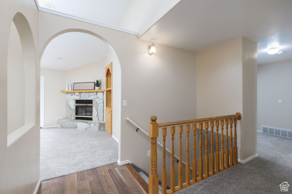 Hall with an upstairs landing, carpet floors, wood finished floors, and baseboards