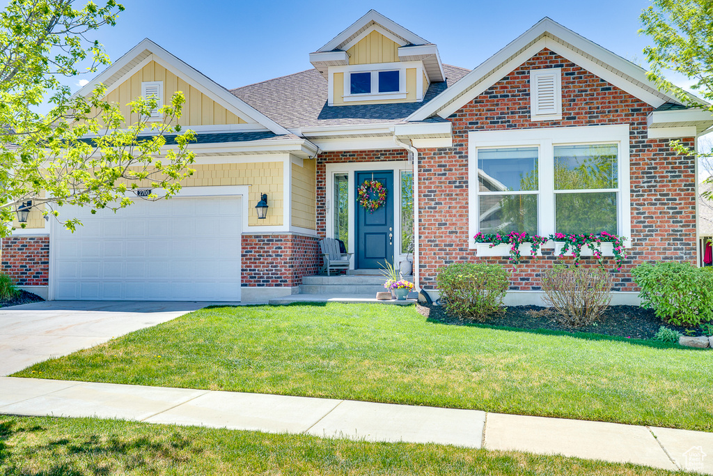 View of front of property with concrete driveway, a front yard, an attached garage, board and batten siding, and roof with shingles