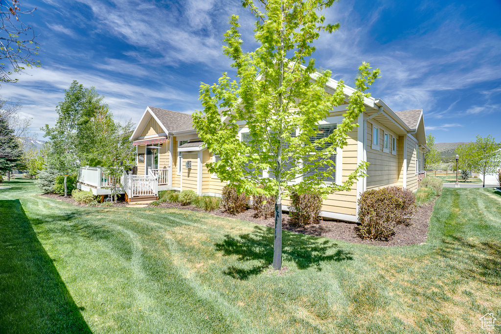 View of front of home with roof with shingles, a front lawn, and a deck