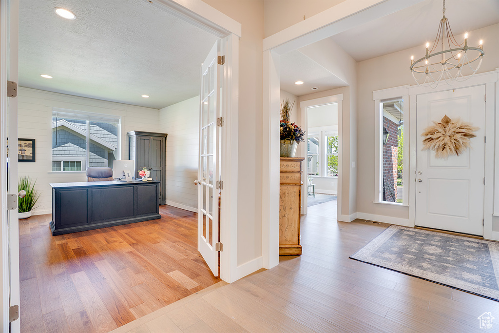 Entrance foyer featuring light wood finished floors, a chandelier, baseboards, french doors, and recessed lighting