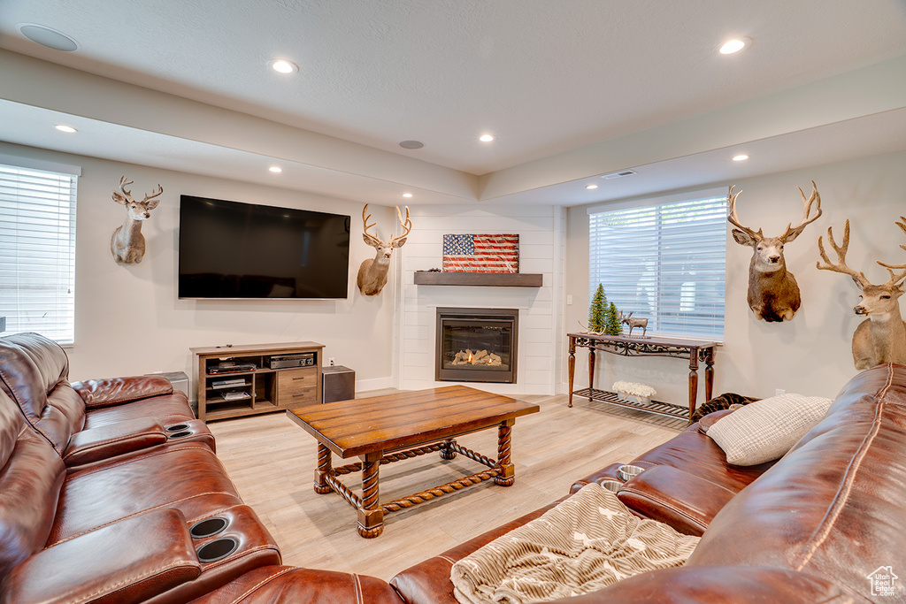 Living room with recessed lighting, a glass covered fireplace, and light wood-style flooring