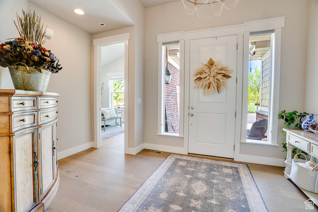 Entrance foyer featuring light wood finished floors, baseboards, a chandelier, and recessed lighting