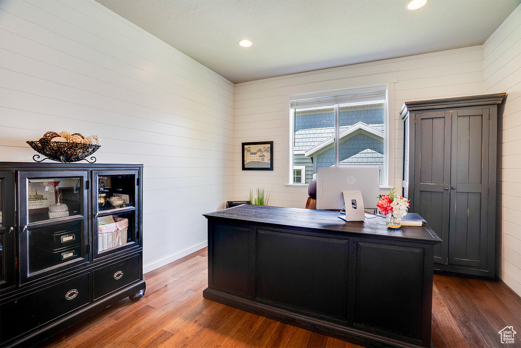 Office space featuring dark wood-type flooring, wooden walls, and recessed lighting