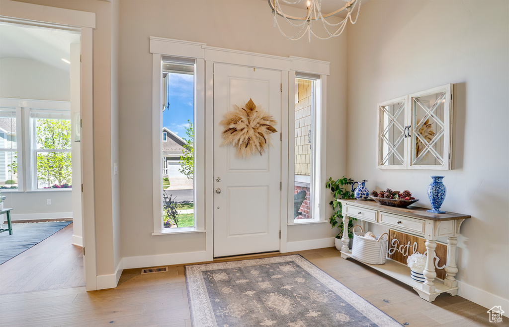 Foyer entrance featuring a chandelier, light wood finished floors, and baseboards