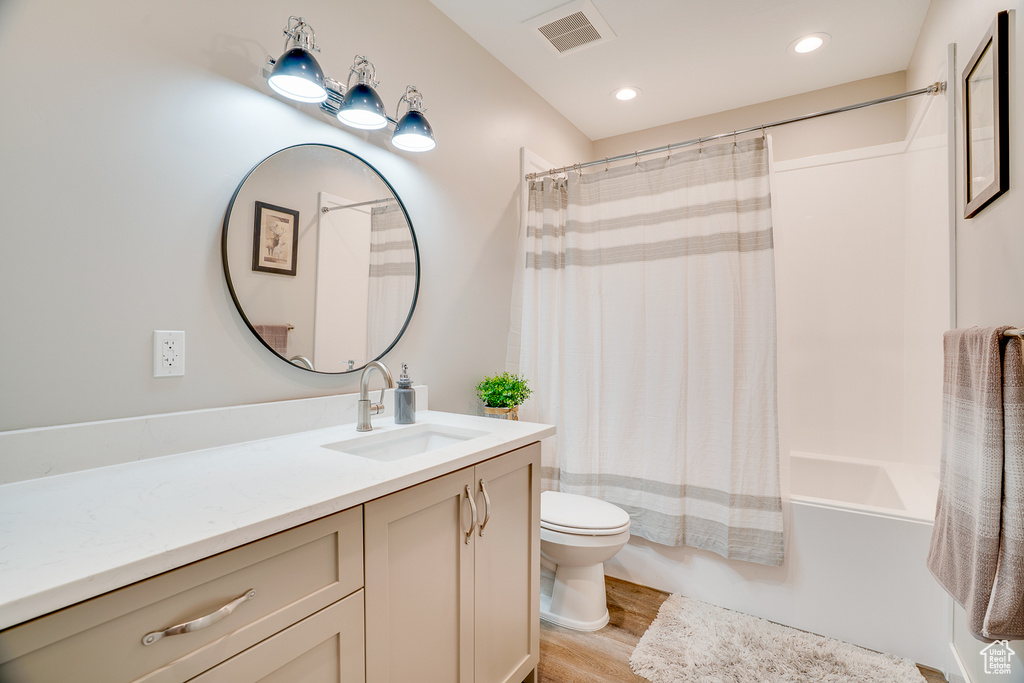 Full bathroom featuring wood finished floors, toilet, vanity, shower / tub combo, and recessed lighting