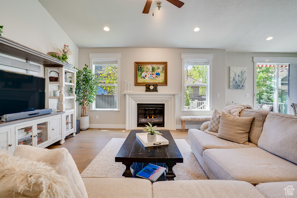 Living area featuring light wood finished floors, healthy amount of natural light, a ceiling fan, recessed lighting, and baseboards