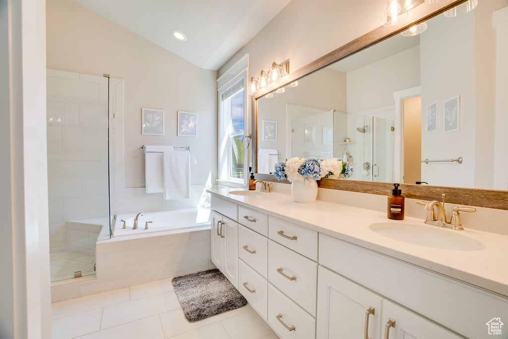 Bathroom featuring a shower stall, double vanity, a garden tub, tile patterned floors, and lofted ceiling