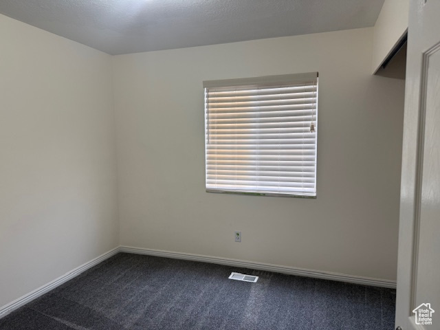 Empty room with dark colored carpet and baseboards