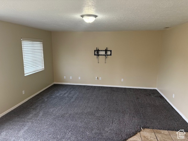 Carpeted empty room with a textured ceiling and baseboards