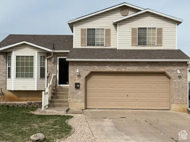 View of front of property featuring an attached garage, brick siding, and concrete driveway