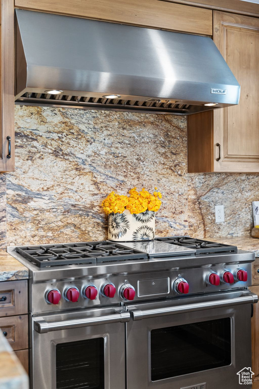 Kitchen with wall chimney range hood, double oven range, and decorative backsplash